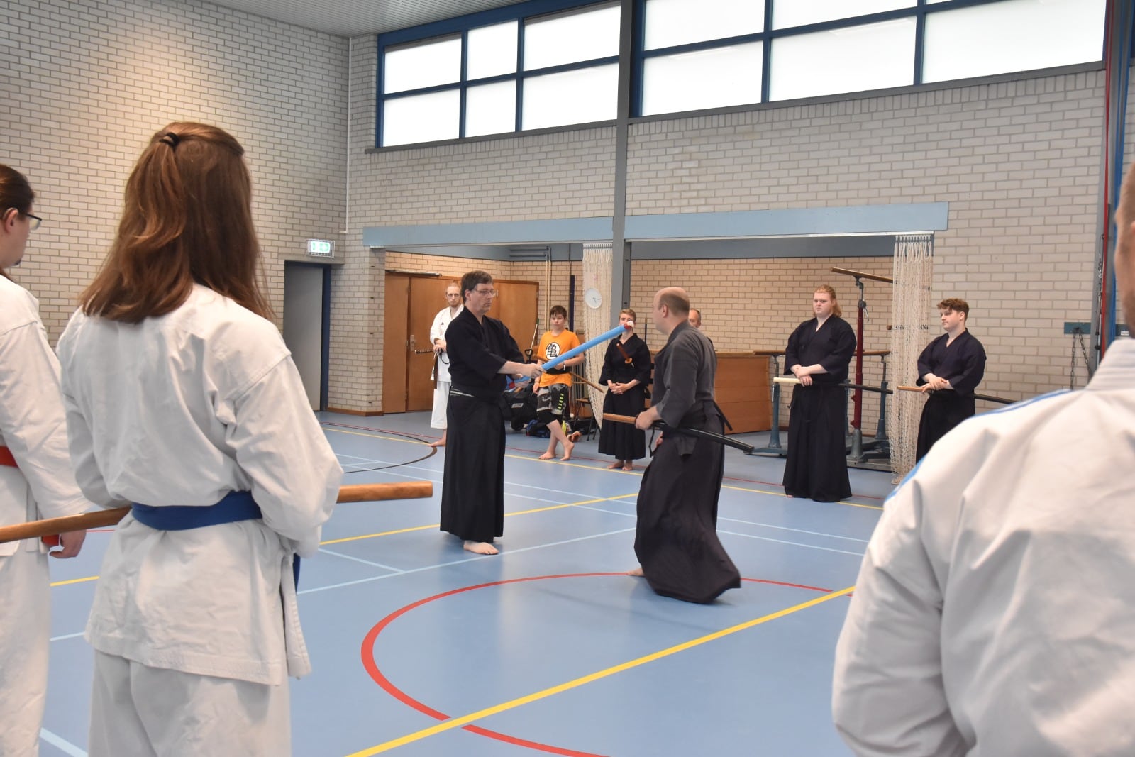 Iaidoka en karateka trainen samen met houten zwaarden in de dojo