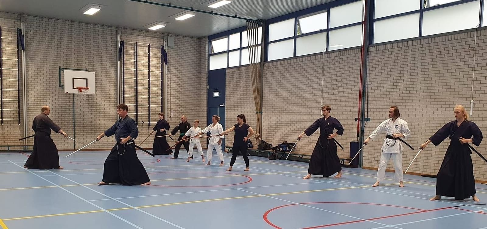 De iaidogroep van Tomo no Kai traint kata met getrokken zwaard in de dojo
