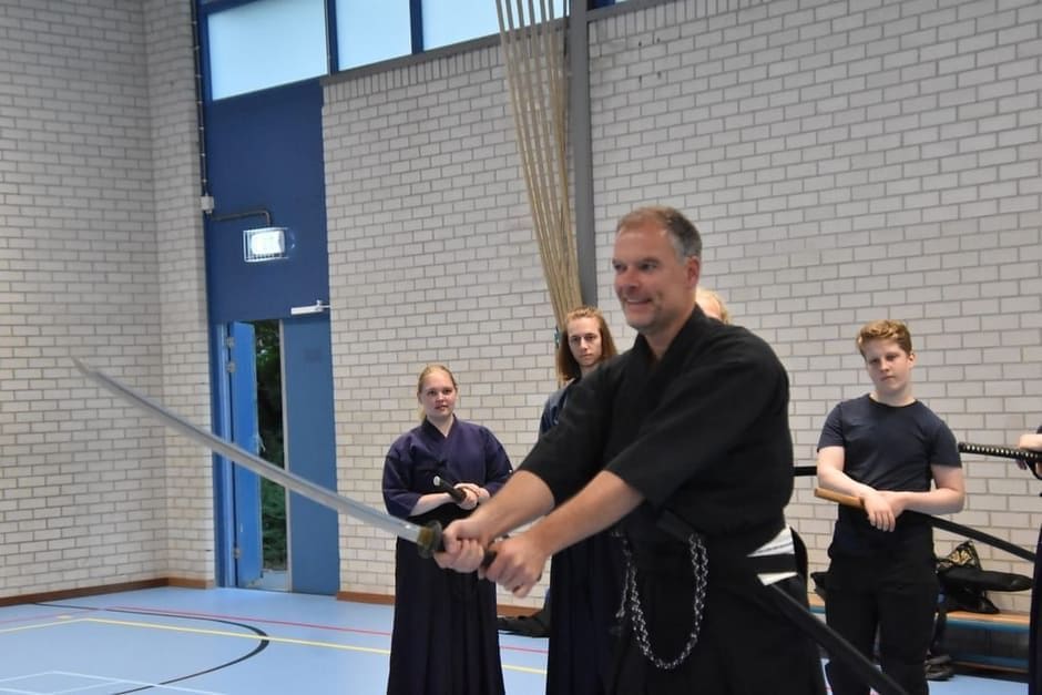 Iaidoles bij Tomo no Kai: de sensei corrigeert een leerling in kniezit