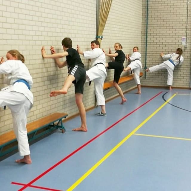 Volwassenen trainen trappen tegen de muur, sommigen in gewone sportkleding