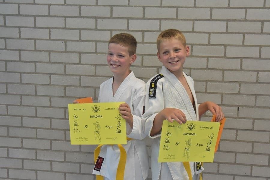 Twee jeugdleden van Tomo no Kai tonen trots hun kyu-diploma Wado-Ryu karate