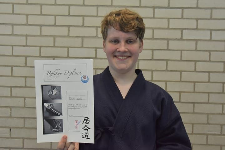 Jeugdlid toont trots zijn diploma na de zomerexamens